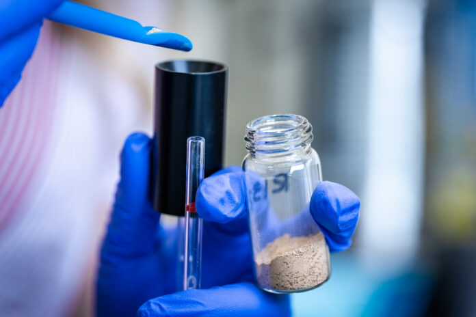 A Ten-Nine researcher handles advanced battery material samples during laboratory testing and evaluation.